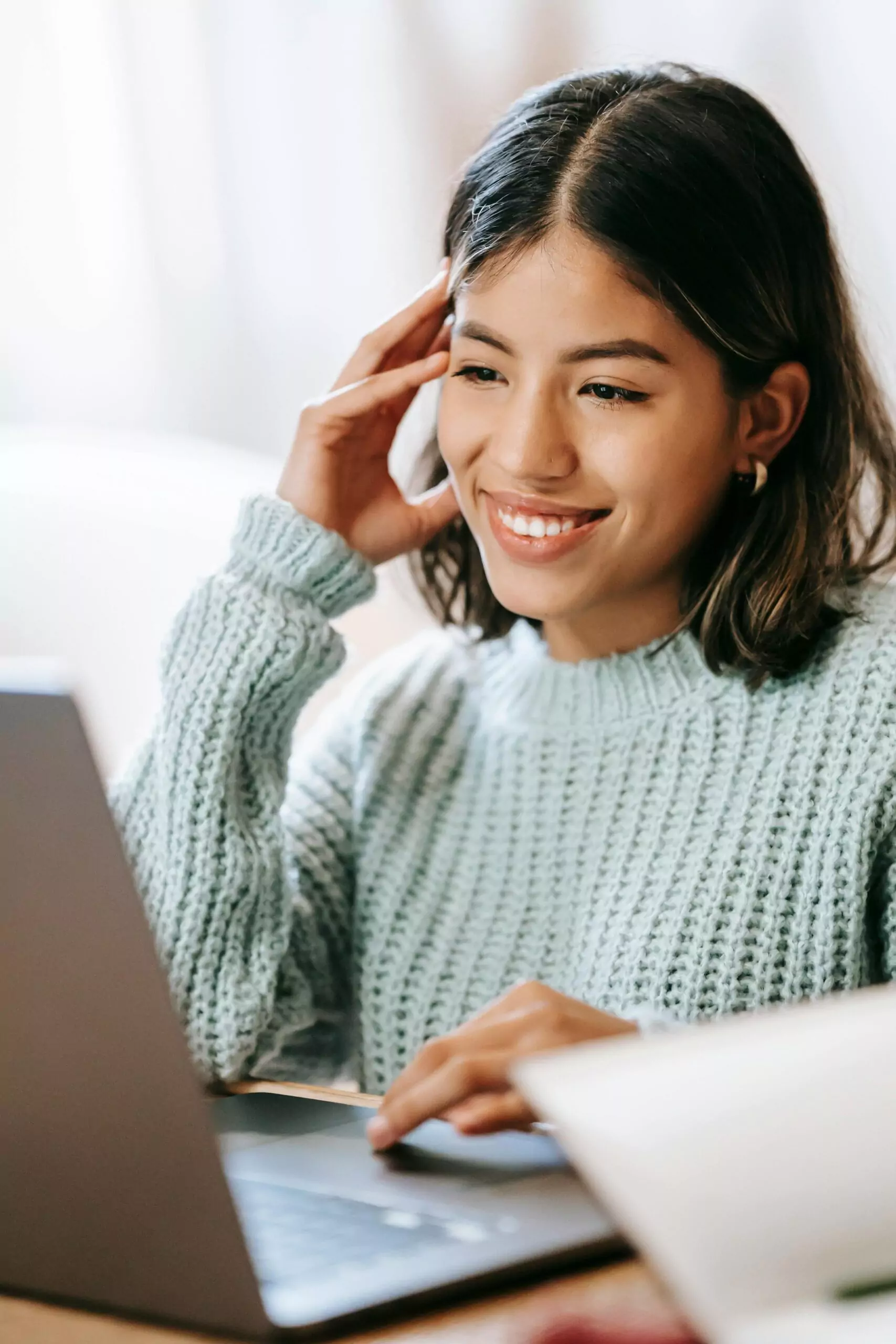 Young woman in light blue sweater using laptop 01